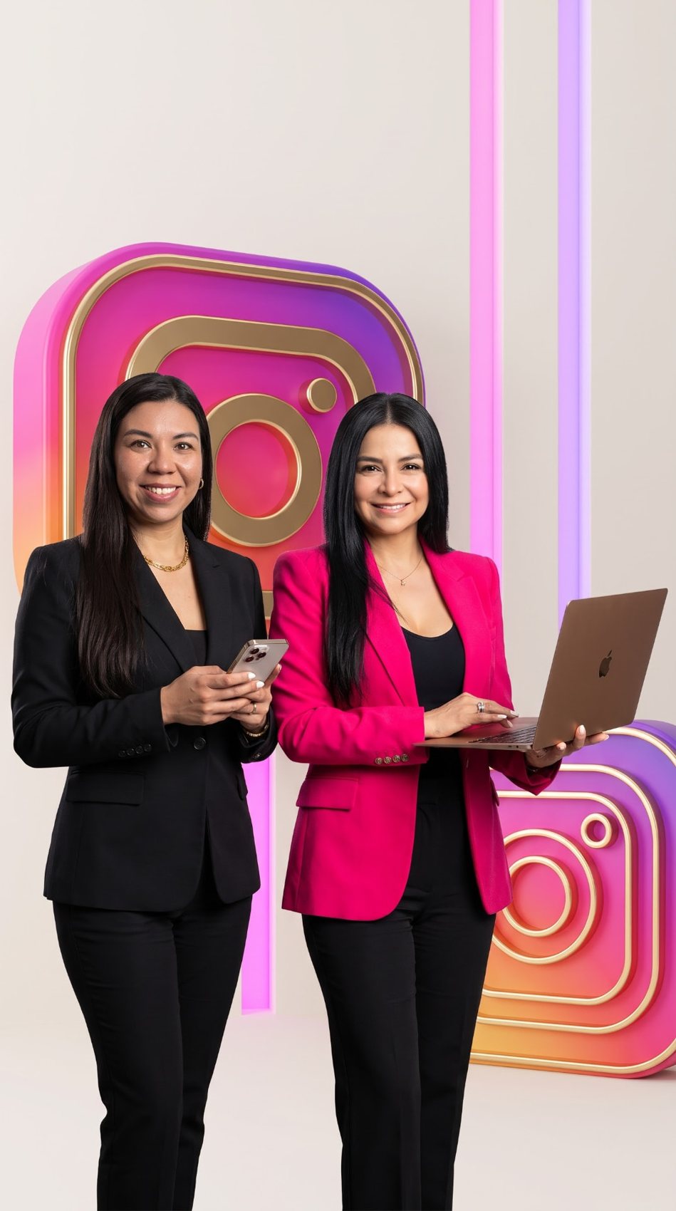Daniela Silva y Josy Salazar de pie frente a logos 3D de Instagram, una con smartphone y otra con laptop